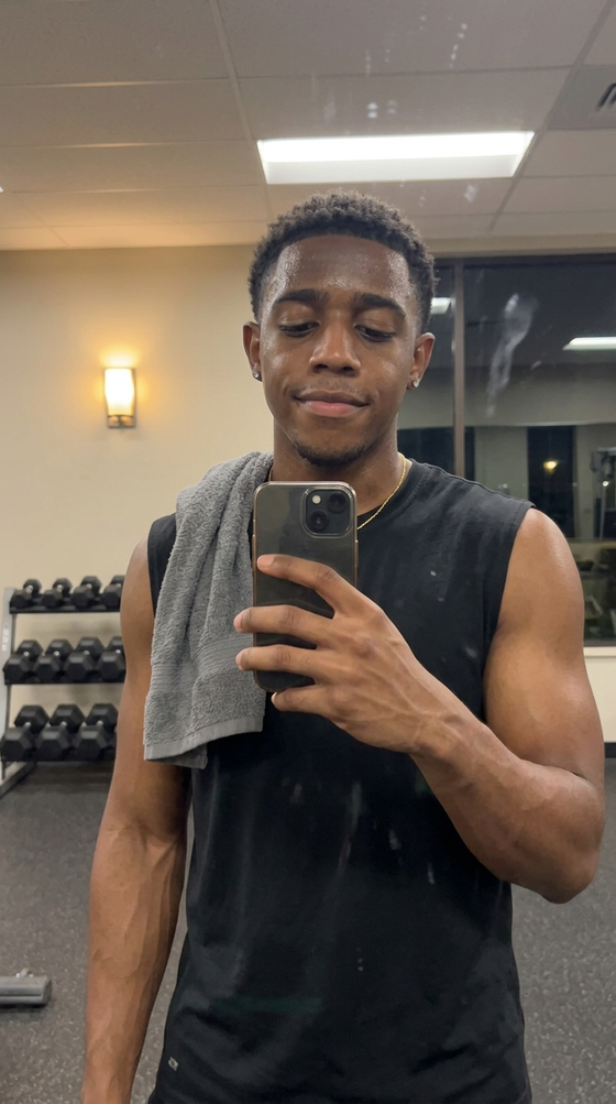 AI-generated creator image: Marcus in a gym mirror selfie after a set, towel on shoulder, evening light